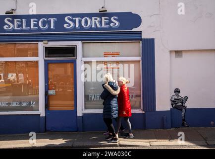 Irland, Dublin, Dalkey, Railway Road, Boy, der Street Art auf der Wand der Select Stores liest Stockfoto