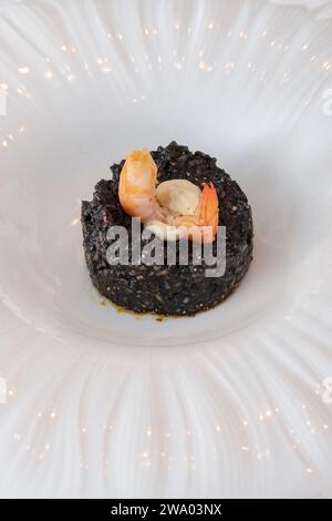Gourmet-Meeresfrüchte-Gericht mit schwarzem Tintenfisch-Reis und einer saftigen Garnele auf dem Dach, ein kulinarisches Erlebnis mit den besten Zutaten Stockfoto