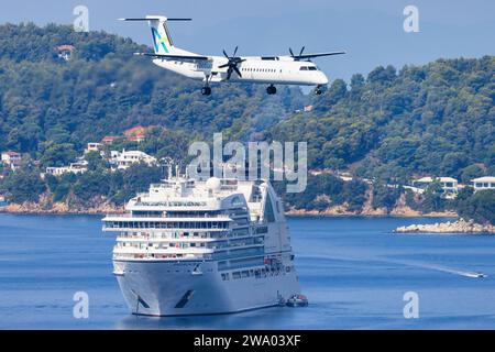 Skiathos, Griechenland - 24. August 2023: Avanti Air Dash 8 mit einem Boot im Hintergrund, das sich dem Flughafen Skiathos nähert Stockfoto