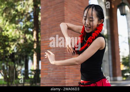 Porträt einer jungen asiatischen Frau, die mit ihren Armen auf der Straße tanzt Stockfoto