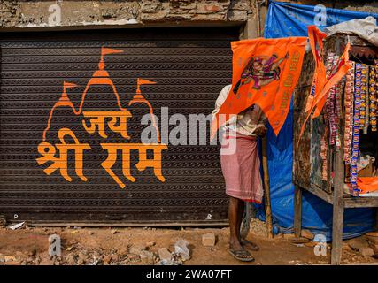 Ayodhya, Indien. Dezember 2023. Ein Arbeiter kauft Gegenstände in einem Geschäft neben einem Kunstwerk, das RAM, eine der verehrtesten Gottheiten des Hindu-pantheons, in Ayodhya, dem angeblichen Geburtsort von RAM, im indischen Bundesstaat Uttar Pradesh darstellt. Ayodhya ist eine antike Stadt in Nordindien, die im Hinduismus eine große religiöse und historische Bedeutung hat, da sie als Geburtsort von Lord Rama gilt, einer Gottheit, die in der hinduistischen Mythologie verehrt wird. Im November 2019 erließ der Supreme Court of India ein historisches Urteil für den Bau eines Hindutempels an der umstrittenen Stelle in Ayodhya. ( Stockfoto