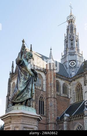 Statue von Laurens Janszoon Coster mit im Hintergrund die Grote Kerk - St. Bavokerk, in der Stadt Haarlem. Stockfoto