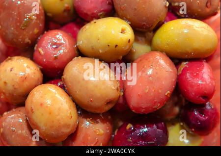 Nahaufnahme eingelegter Oliven in roten und grünen Farben im Hintergrund Stockfoto