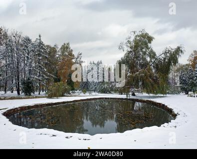 Erste Herbst plötzliche Schnee im Stadtpark und kleinen Teich Stockfoto