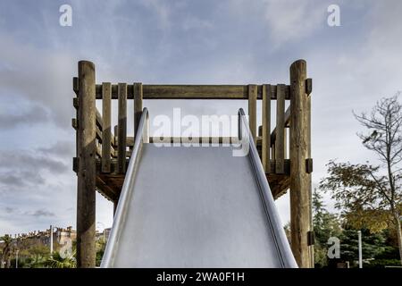 Oben auf einer großen Metallrutsche mit Holzstruktur in einem Kinderspielplatz an einem Tag mit klarem Himmel Stockfoto