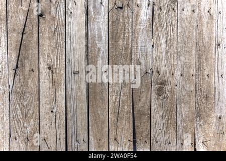 Ein Holzdielen-Zaun mit alten gefallenen Stacheln und verderbtem Holz Stockfoto