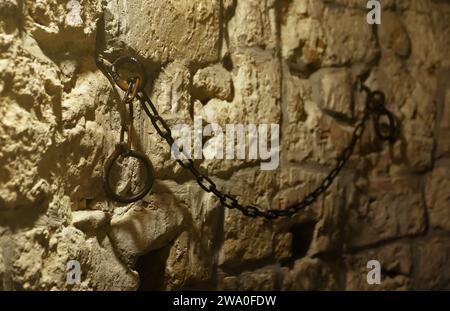 Sklaverei und Knechtschaft starke Stahlfesseln an der Steinmauer im Burgkeller oder Grabmal Stockfoto