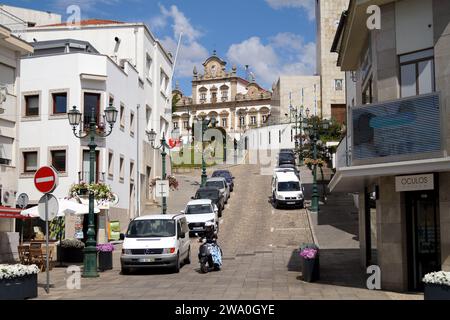 Steile Straße im Zentrum der Stadt, mit dem Rathaus im alten Herrenhaus den Hügel hinauf, Mirandela, Portugal Stockfoto