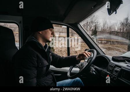 Junger Lkw-Fahrer, der hinter dem Lenkrad sitzt und den Frachttransport bestellt Stockfoto