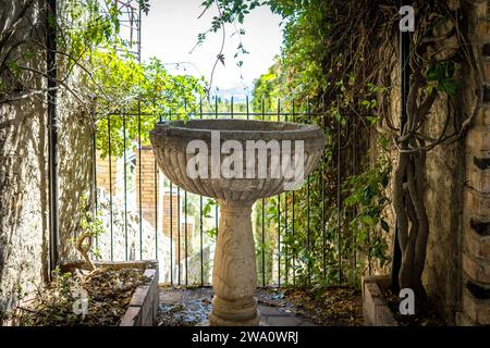 Der antike Brunnen ist umgeben von Ästen mit grünen Blättern in Taormina, Sizilien Stockfoto