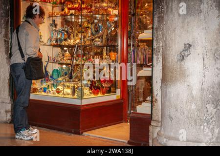 Venedig Italien - 10. Mai 2011; Frau, die Glaskunst im Schaufenster auf dem Markusplatz ansieht. Stockfoto