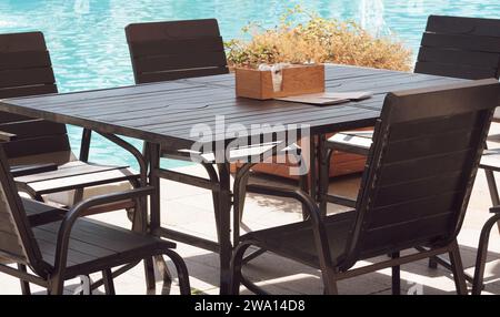 Holzstuhl und Tisch in der Nähe des Pools. Leerer Platz am Pool, Sommerhintergrund. Stockfoto