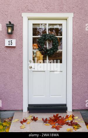 Haus Nr. 15 mit hellrosa Wänden und weißer getäfelter Eingangstür Stockfoto