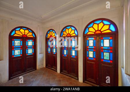 Alte Holztüren mit bunten Buntglasfenstern in einem der Räume des Tabatabaei-Hauses, einem historischen Herrenhaus, das um 1880 in Kaschan, Iran, erbaut wurde Stockfoto