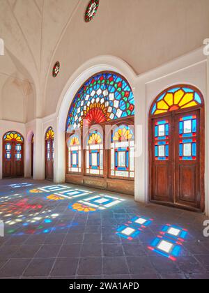 Zimmer mit bunten Buntglasfenstern im Tabatabaei House, einem historischen Herrenhaus, das um 1880 in Kaschan, Iran, erbaut wurde. Stockfoto