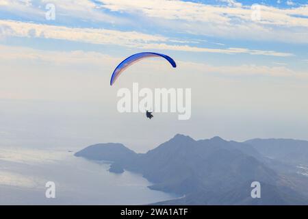 Gleitschirmflieger, die von einem Gipfel des Tahtali-Berges in der Nähe von Kemer in der Provinz Antalya in der Türkei fliegen. Konzept von aktivem Lebensstil und Extremsportabenteuer Stockfoto
