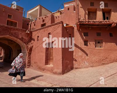 Eine einheimische Frau in traditioneller Kleidung spaziert in einer schmalen Straße im historischen Dorf Abyaneh, Natanz County, Iran. Stockfoto
