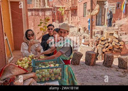 Chinesische Touristen kaufen frische Äpfel von einem lokalen Straßenverkäufer im historischen Dorf Abyaneh, Natanz County, Iran. Stockfoto