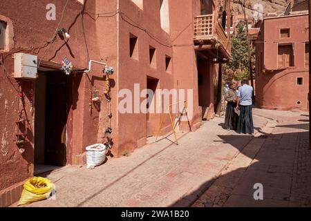 Zwei einheimische Männer in traditioneller Kleidung unterhalten sich in einer engen Straße im historischen Dorf Abyaneh, Natanz County, Iran. Stockfoto