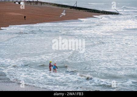 Hastings, East Sussex, Großbritannien 1. Januar 2024. Zwei unerschrockene Badende trotzen dem kalten Meer am frühen Morgen am Hastings Harbour an einem grauen Neujahrstag. Carolyn Clarke/Alamy Live News Stockfoto