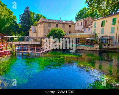 Zentrum des Dorfes Fontaine de Vaucluse umgeben von farbenfroher Natur im Sommer. Klares und kristallines Wasser der Quelle des Sorga-Flusses. Stockfoto