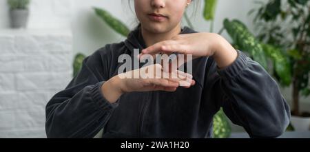 Wunderschönes, lächelndes, taubes Mädchen, das Gebärdensprache benutzt. Stockfoto