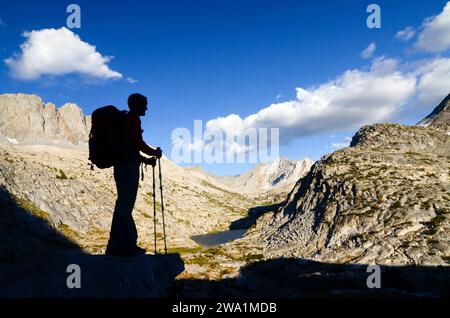 Eine Silhouette eines Rucksacktouristen mit Wanderstöcken, die vom Cirque Pass auf der Sierra High Route, CA. Stockfoto