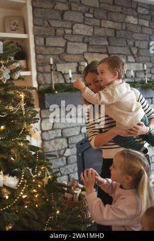 Mutter und Kinder schmücken fröhlich den weihnachtsbaum der Familie Stockfoto