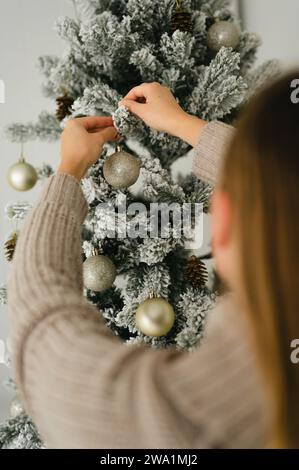 Rückansicht einer Frau, die den weihnachtsbaum mit Weihnachtsschmuck verziert Stockfoto