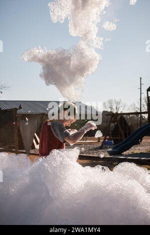 Glückliches Kind, das in riesigen Schaumblasen im Park spielt Stockfoto