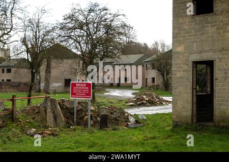 Das „verlorene Dorf“ von Imber, Salisbury Plain, Wiltshire, Großbritannien, zeigt die Kirche, Imber Court (grüne Fensterläden) und die Armee-Trainingshäuser und Warnschild. Stockfoto