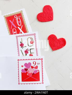 Valentinstag-Briefmarken auf Briefumschlägen mit roten Herzen Stockfoto