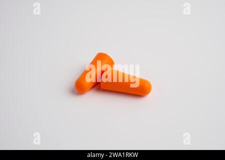 Ein Paar orangefarbene Ohrstöpsel auf weißem Hintergrund Stockfoto