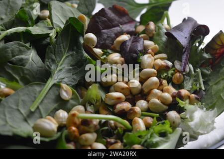 Gesundes, gesundes, hochwertiges Essen, frische Salate mit Rucola, Basilikum und Erdnüssen in einer großen Glasvase. Stockfoto