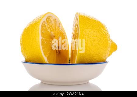 Zwei halb gelbe saftige Zitrone auf einer weißen Keramikuntertasse, Nahaufnahme, isoliert auf weiß. Stockfoto