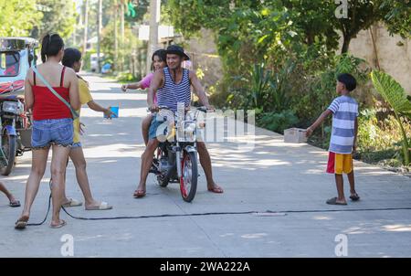 Tiaong, Philippinen. 1. Januar 2024: In ländlichen Provinzen bauen philippinische arme Familien freundliche mautpflichtige Straßen mit einem Seil und einem Happy New Year-Schild auf. Autos, Dreiräder oder Fußgänger werden ermutigt, „Dankspenden“ zu machen, in der Regel nur ein paar Pesos, unverbindlich, immer mit einem Lächeln und manchmal mit wenigen Tanzschritten geschmückt. Eine Tradition, die nur in bestimmten Regionen praktiziert wurde und sich seit den harten Tagen der COVID 19-Epidemie auf fast das gesamte Land ausgebreitet hat. Beispielsweise können Sie über 1 km an bestimmten Stellen bis zu 15 Stopps zählen. Quelle: Kevin Izorce/Alamy Live News Stockfoto