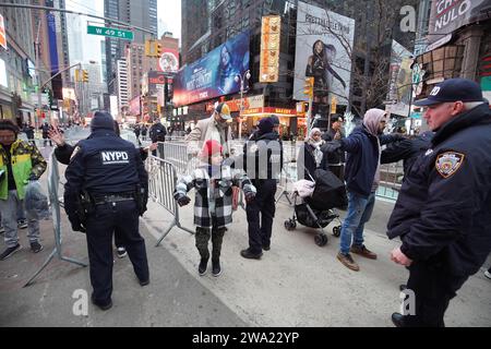 Polizisten des New Yorker Polizeidezernats (NYPD) führen eine Sicherheitskontrolle durch, bevor Menschen den Times Square betreten. Die Silvesterfeier am Times Square 2024 in New York City markiert eine monumentale Rückkehr nach der COVID-19-Pandemie und zieht Tausende von begeisterten Menschen dazu an, am legendären Countdown teilzunehmen und das neue Jahr zu begrüßen. Wie es die Tradition vorschreibt, fesselt der schillernde Ball Drop die Menschenmassen und signalisiert den Übergang zu 2024. Mit der Jahreswende steigt eine atemberaubende Konfetti-Kaskade vom Himmel ab und verwandelt das geschäftige Stadtbild in einen faszinierenden Farbschauer Stockfoto