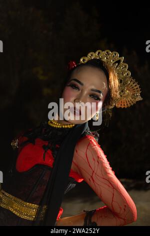 Eine balinesische Frau trägt schweres Make-up mit rosa roten Lippen und scharfem Haar, wenn sie nachts posiert Stockfoto