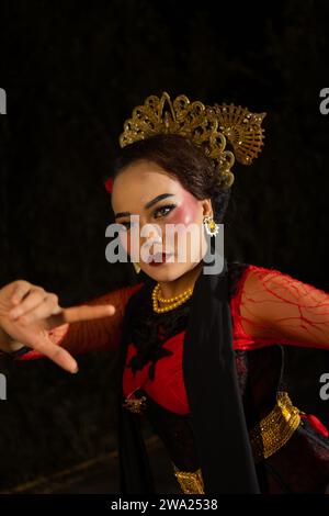 Eine balinesische Frau trägt schweres Make-up mit rosa roten Lippen und scharfem Haar, wenn sie nachts posiert Stockfoto