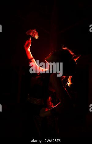 Silhouette einer Tänzerin mit Schmuck mitten in der Stille der Nacht mit rotem Licht in der Nacht Stockfoto