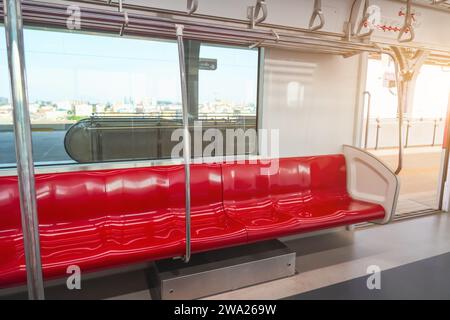 Innenraum eines Personenkraftwagens eines Pendlerzuges. Rote Kunststoffsitze und Chrom-Handläufe in einem elektrischen Zugwagen. Stockfoto