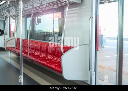 Innenraum eines Personenkraftwagens eines Pendlerzuges. Rote Kunststoffsitze und Chrom-Handläufe in einem elektrischen Zugwagen. Stockfoto