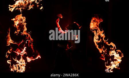 Die Silhouette einer Tänzerin, die glitzernden Schmuck hält und im Dunkeln scharf aussieht, während nachts ein Feuer im Hintergrund brennt Stockfoto