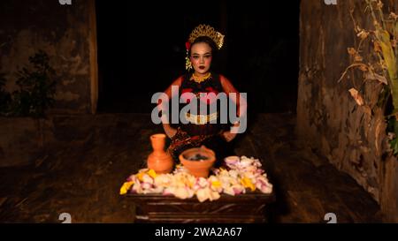 Eine Tänzerin sitzt anmutig und beginnt ihr Ritual vor schönen Darbietungen in der Nacht Stockfoto