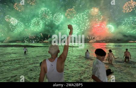 Rio de Janeiro, Brasilien. Januar 2024. Ein junger Mann hebt seine Faust mit einem Satz Rosenkranzperlen, während über 2 Millionen Nachtschwärmer in Rio de Janeiro im neuen Jahr mit einem riesigen Feuerwerk am Copacabana Beach läuten. (Credit Image: © Bob Karp/ZUMA Press Wire) NUR REDAKTIONELLE VERWENDUNG! Nicht für kommerzielle ZWECKE! Stockfoto