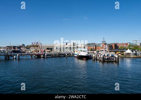 Anlegestelle der Personenfähren der Kieler Fördeschiffahrt, Passagiere erwarten das Ankommen der planmäßgen Fährverbindungen die Klappbrücke über die Hörn *** Passagierfähren des Docks Kieler Fördeschiffahrt, Passagiere erwarten die Ankunft der Linienfähre links von der Klappbrücke über die Hörn Stockfoto