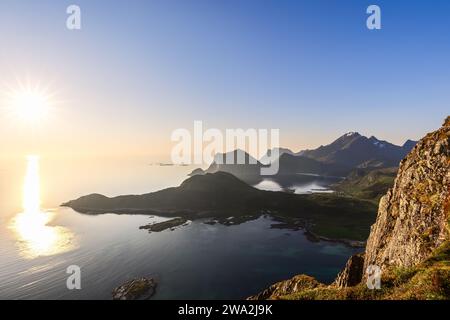 Die Mitternachtssonne strahlt ein warmes Leuchten über die Lofoten-Inseln, von Offersoykammen aus gesehen, mit Sonnenstrahlen, die sich vom ruhigen Wasser reflektieren Stockfoto