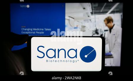 Person, die ein Mobiltelefon mit dem Logo des US-amerikanischen Biotech-Forschungsunternehmens Sana Biotechnology Inc. Vor der Website des Unternehmens hält. Schwerpunkt auf dem Display des Telefons. Stockfoto