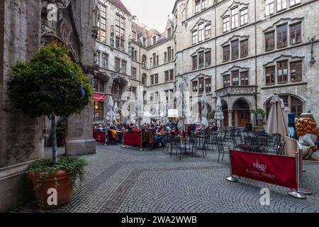 Menschen auf der Terrasse im Innenhof des Neuen Rathauses am Marienplatz in München. Stockfoto