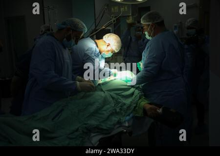 Khan Yunis, Gaza. Dezember 2023 31. Der amerikanische Chirurg Imad (C) operiert am Montag, 1. Januar 2024 in einem Operationssaal des Europäischen Krankenhauses in Khan Yunis im südlichen Gazastreifen an einem Patienten. Chirurg Imad kam, begleitet von einer Gruppe von Ärzten, vom Grenzübergang Rafah zu Ägypten nach Gaza, um chirurgische Operationen für Palästinenser durchzuführen, die im Krieg verletzt wurden. Foto: Ismael Mohamad/UPI Credit: UPI/Alamy Live News Stockfoto